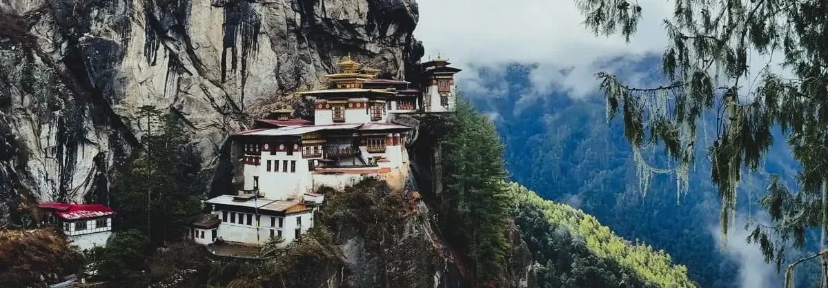 The iconic Tiger’s Nest Monastery perched on a cliffside in Bhutan, framed by mist and evergreen trees